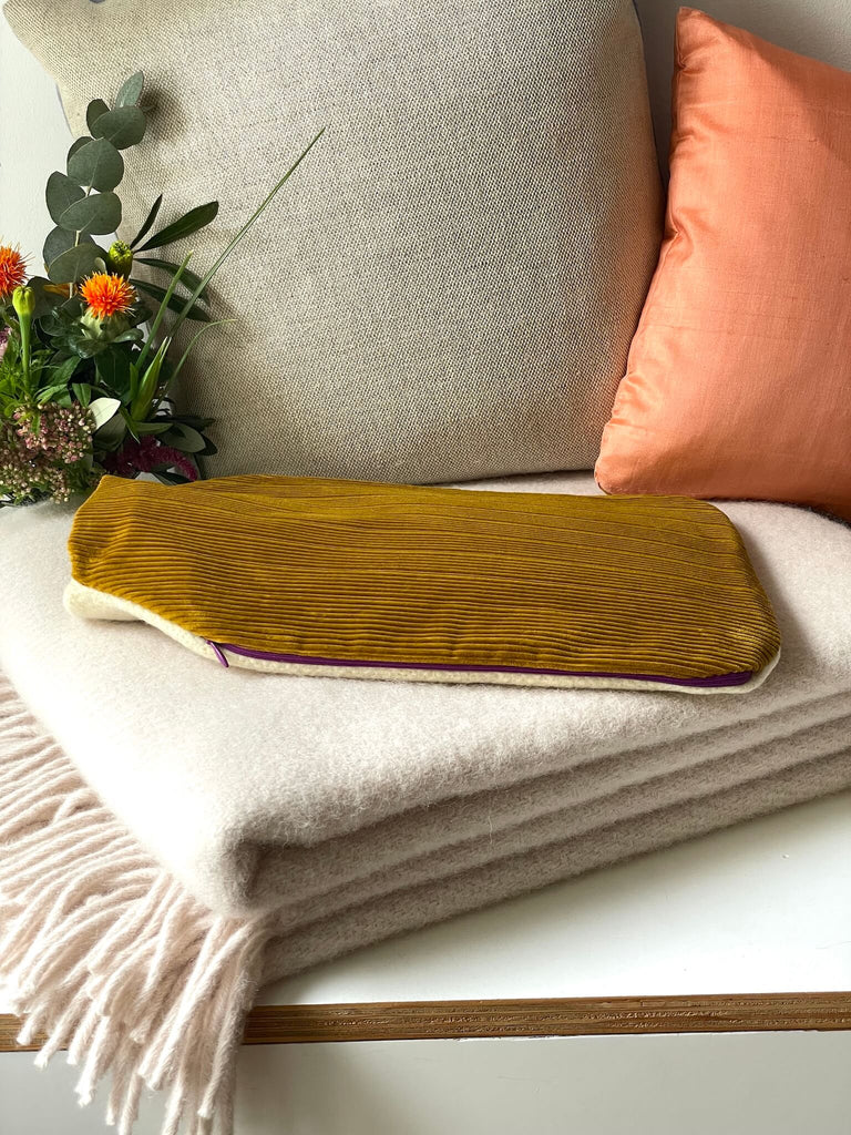 Handgefertigter Wärmflaschenbezug in gelb und beige, mit Wärmflasche auf einer rosa Wolldecke von D&T Design 